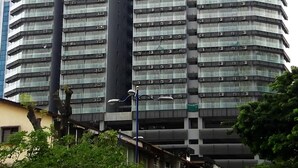 A high-rise building with multiple floors and balconies, featuring a modern architectural design.