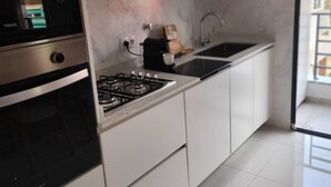 Une cuisine moderne avec des armoires blanches, une cuisinière noire et un pare-feu en marbre.