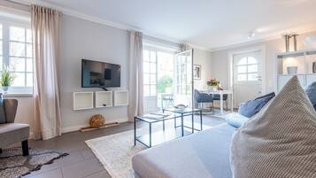 Ein modernes Wohnzimmer mit Sofa, Fernseher und Essbereich mit Tisch und Stühlen.