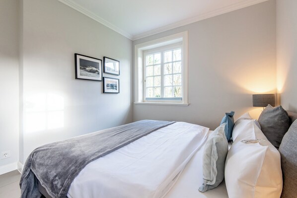 Une chambre à coucher avec un lit, une fenêtre et une lampe fixée au mur.