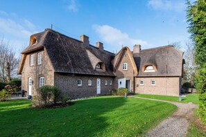 En stor, historisk murstensbygning med flere skorstene og buede vinduer.