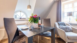 En matplats med ett bord dukat för fyra personer, en blomsterdekoration i mitten och en modern stol med en mjuk kudde.