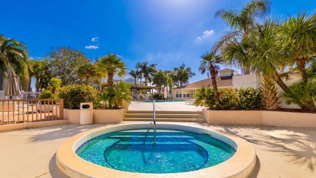 Una piscina circular con un centro azul cristalino, rodeada por un borde de baldosas color beige.