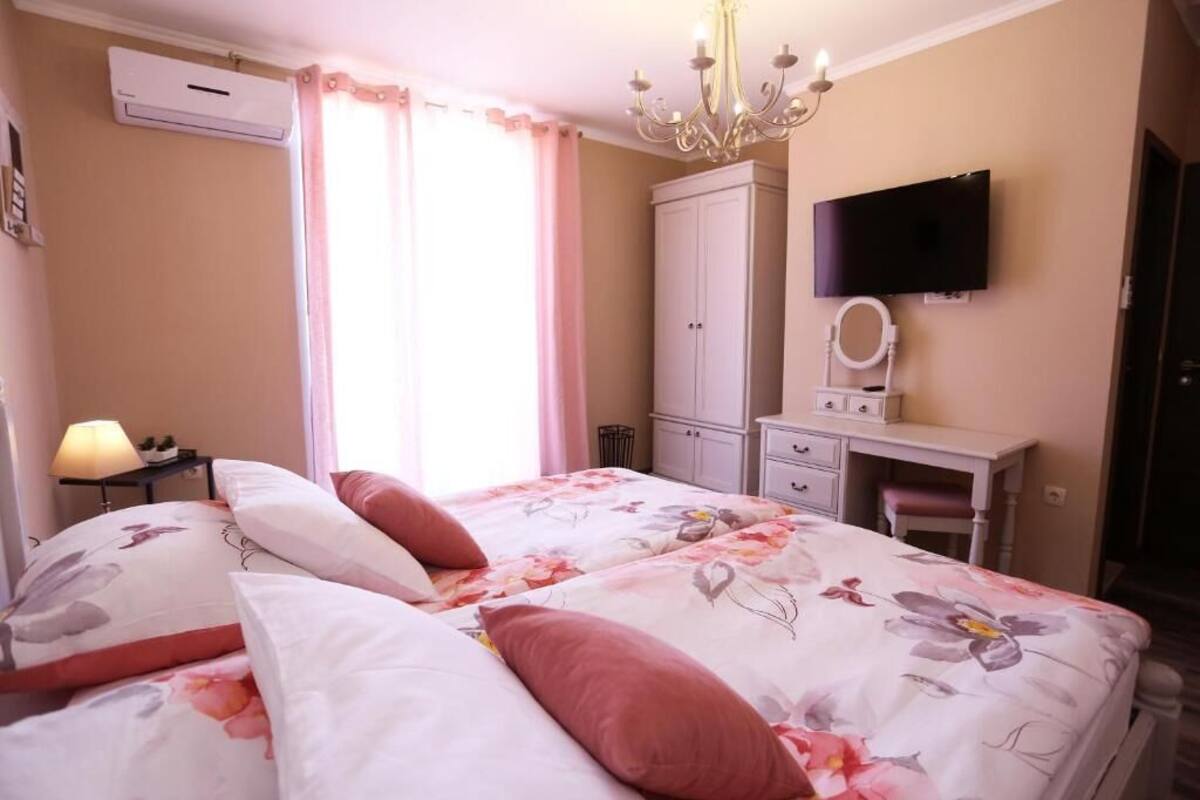 Une chambre avec deux lits, un bureau, une télévision et une armoire.