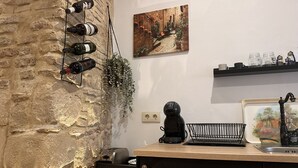 A kitchen with a stone wall, wine bottles, a coffee machine, and a painting. - Apartamento Santa Clara - Ole Solutions (Jerez de la Frontera)