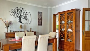 A dining area with a wooden table, four chairs, a decorative tree wall art, a cabinet with glass doors, and a framed picture on the wall. - Villa Moreno - Ole Solutions (Puerto de Santa María)