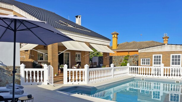 A swimming pool with a white fence, lounge chairs, and umbrellas. - Villa Moreno - Ole Solutions (Puerto de Santa María)