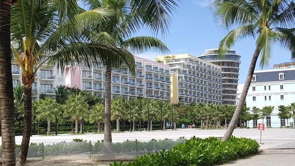 A modern hotel with multiple floors, palm trees, and a clear sky.