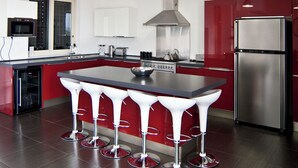 A modern kitchen with a central island, stainless steel appliances, and red cabinetry.