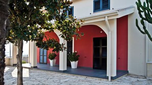 A building with red arches and white walls, potted plants, and a cobblestone courtyard.