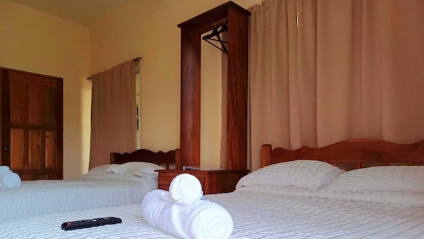 A hotel room with two beds, a wooden headboard, a large mirror, and a remote control on the bed. - Southern Corner Motel & Restaurant (Independence and Mango Creek)