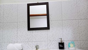 A bathroom with a tiled wall, a mirror, a sink, a towel, a soap dispenser, and a tissue box. - Southern Corner Motel & Restaurant (Independence and Mango Creek)