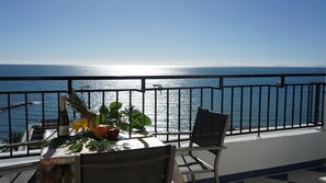 Enjoy a romantic ocean view from this balcony, complete with a table set for two and a refreshing selection of fruits.