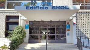 La entrada del Edificio SKOL, con un cartel sobre la puerta, cajeros automáticos y una escalera que lleva a la entrada.