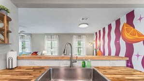Una cocina moderna con encimera de madera, pileta de acero inoxidable y un mural de pared colorido.