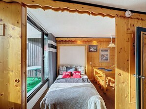 Cozy bedroom with a large bed, wooden desk, and window.