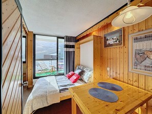 Relax in a spacious room with a large bed, wooden table, and a beautiful view of the outdoors.