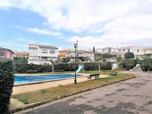 A residential area with a swimming pool, benches, and a playground.