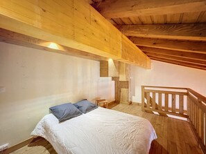 Ein Schlafzimmer mit Holzboden, einem Bett mit weißer Bettwäsche und einem kleinen Nachttisch.
