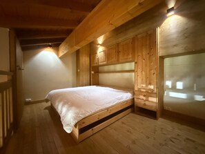 A wooden room with a bed, built-in cabinets, and a sloped ceiling.