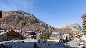 A mountainous town with traditional wooden buildings, a parking area, and a clear view of the surrounding peaks. - Charming Apartment in Val d'Isère Center - 4 Guests, Balcony, WiFi (Val-d'Isère)