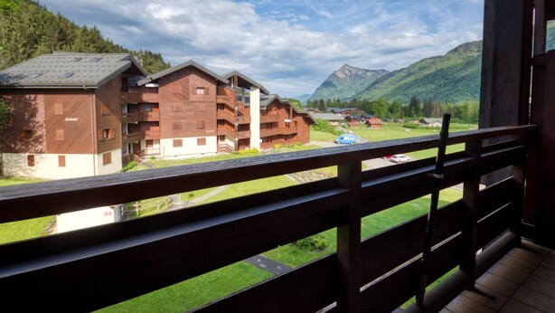A wooden building with balconies, a view of a mountain, and a green landscape. - Charming duplex for 5 near Blue Lake (Morillon Village)