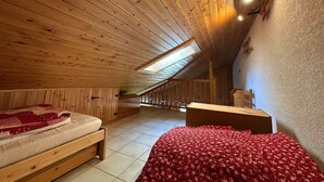 A wooden room with a sloped ceiling, a bed, a desk, and a window. - Charming duplex for 5 near Blue Lake (Morillon Village)