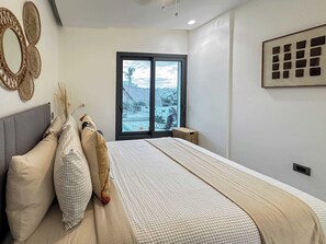 Un dormitorio con cama, un ventanal con vistas y un espejo montado en la pared.
