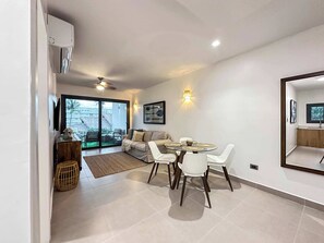 Una sala de estar moderna con comedor, un sofá, una mesa de centro y vistas al exterior.