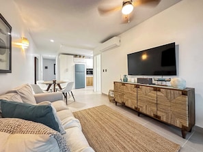 Una sala de estar moderna con un sofá, una mesa de centro y un televisor sobre un mueble de madera.
