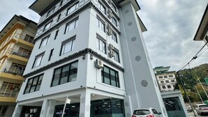 A multi-story building with a modern architectural design, featuring large windows and a prominent entrance. - The Gochukha Hotel (Thimphu)