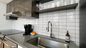 A modern kitchen with a stainless steel sink, a coffee maker, and a bottle of hand soap.