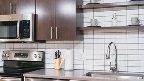 Eine moderne Küche mit Edelstahlgeräten, einer Mikrowelle, einem Backofen und einem Spülbecken mit Armatur.