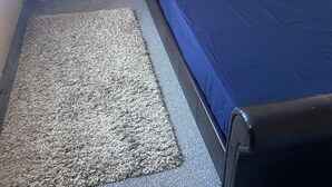 Un dormitorio con cama, mesita de noche y alfombra.