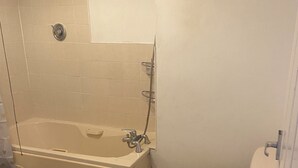 Un baño con bañera, inodoro y dos alfombras en el suelo.