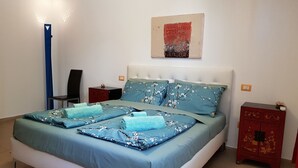 En pænt redt seng med blomstret sengetøj, en sengegavl og to natborde med lamper.