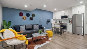 A modern living room with a sofa, coffee table, and a dining area with a small table and chairs.