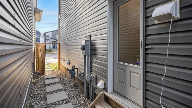 A narrow pathway leading to a house with a closed door and a window with a shutter.