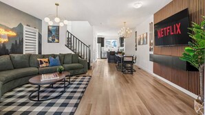 Een moderne woonkamer met een bank, salontafel en een eethoek met stoelen en een tafel.