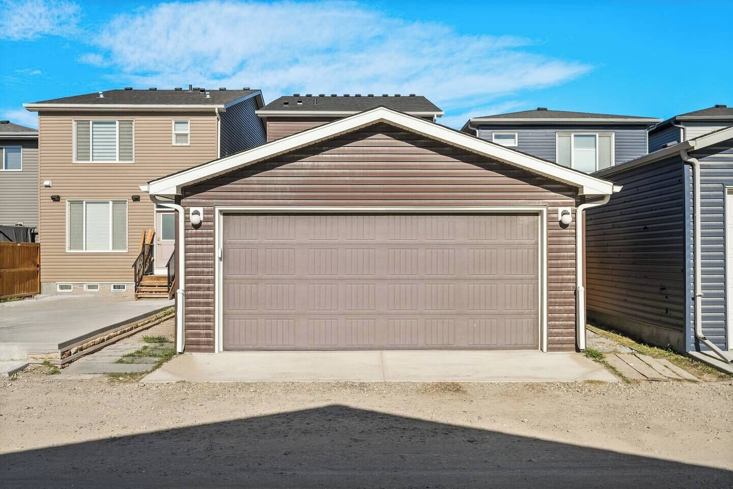 A residential garage with a brown roof and white trim, adjacent to a house with beige siding and a visible chimney.