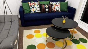 A living room with a blue sofa, a grey sofa, and a two-tiered black coffee table with gold legs. - A Vibrant 3-bedroom House With Ample Parking (Derby)