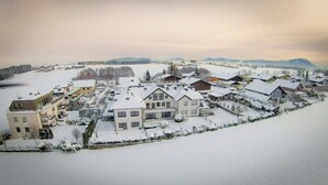 A snow-covered residential area with houses and a large building, likely a hotel, featuring multiple floors and balconies.