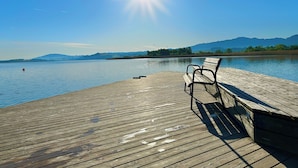 Une jetée en bois s’étendant sur une étendue d’eau calme, avec un banc et une bouée.