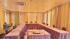 Un salón de conferencias con una larga mesa, sillas y un proyector.