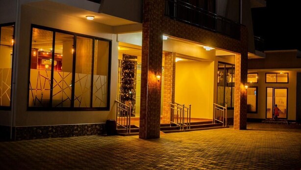 Fachada de hotel de ladrillo, con amplias ventanas y una escalera que conduce a la entrada.