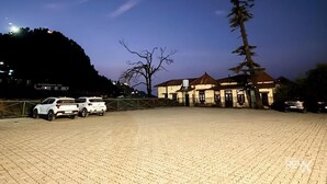 A paved parking area with two white cars parked. - Hotel Sunny Cot - Free Mall shuttle and Parking (Dehradun)