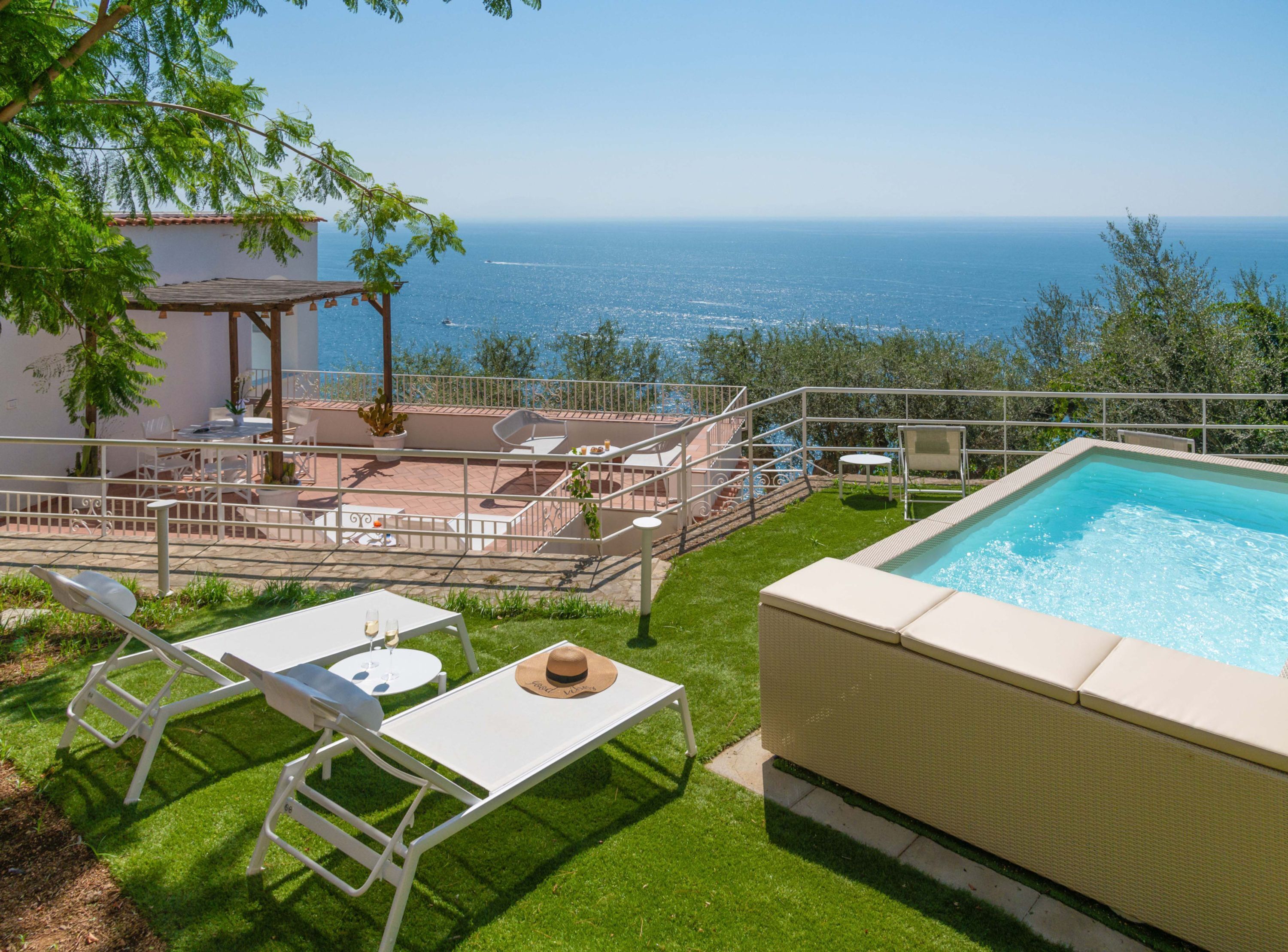 Ein Poolbereich mit Meerblick, Sitzgelegenheiten im Freien und einer überdachten Terrasse.