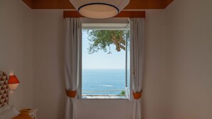 A bedroom with a large window, a bed, a nightstand, and a lamp. - Villa Jacaranda in Praiano (Praiano)