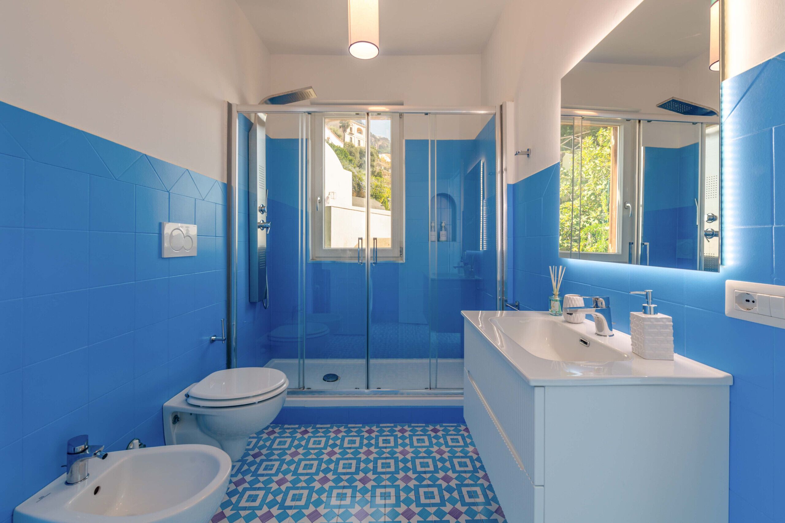 Une salle de bain équipée d’une douche, de toilettes, d’un bidet et d’un lavabo avec un miroir.