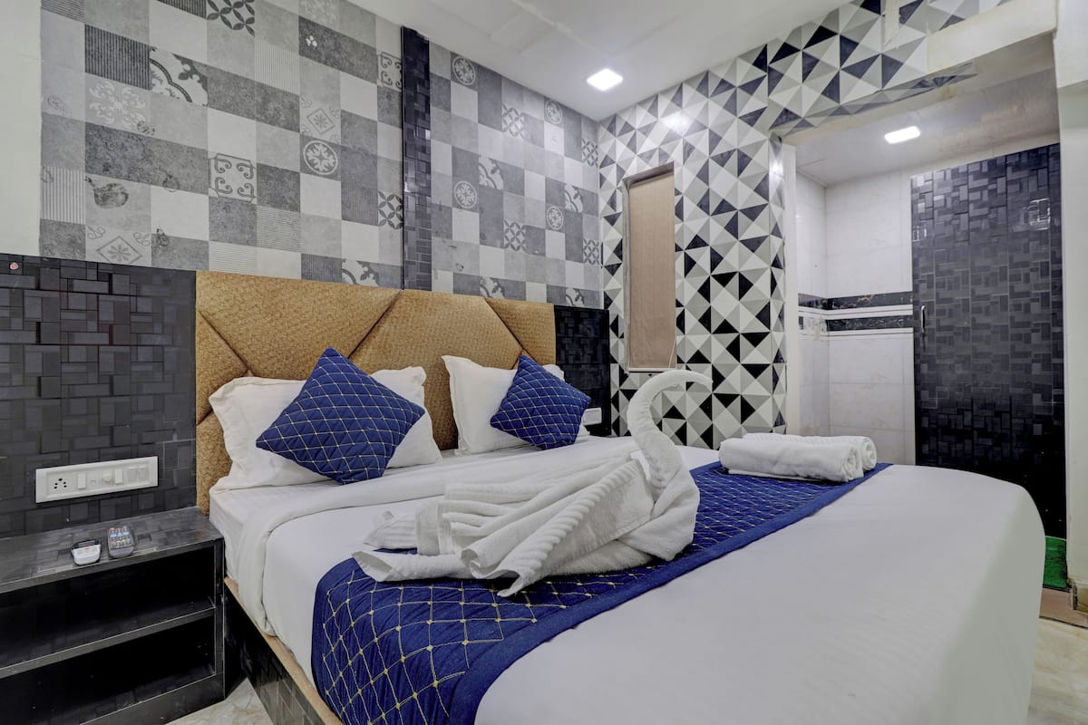 A hotel room with a large bed, a headboard, and a wall with patterned tiles.